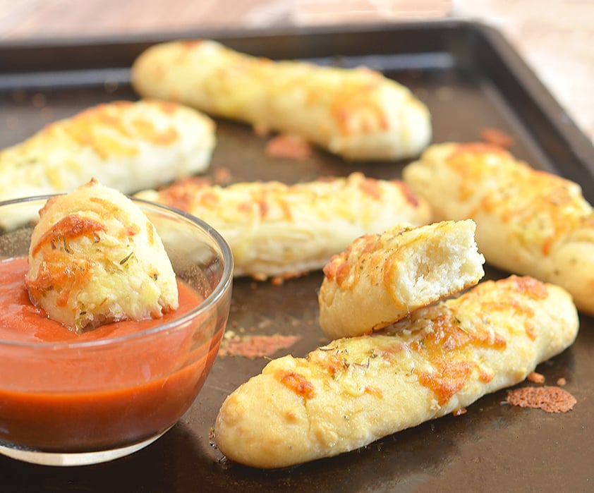 Two-Ingredient Breadsticks hot and fresh on a baking sheet and served with marinara sauce.