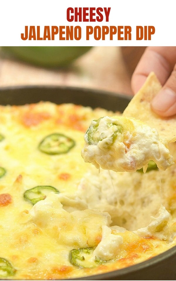 dipping corn chips in Cheesy Jalapeno Popper Dip baked in a cast iron skillet