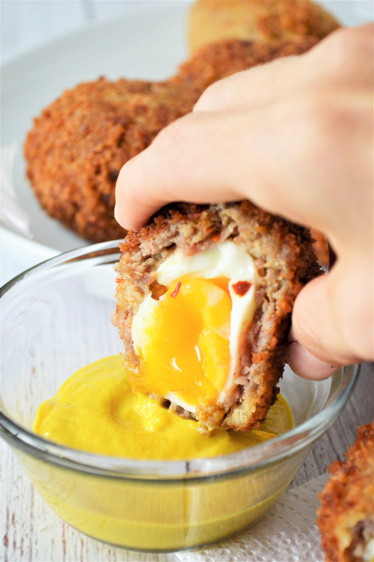 dipping scotch eggs in mustard