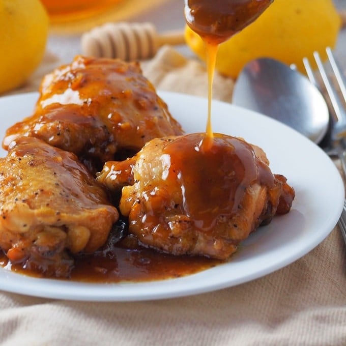 pouring honey lemon sauce on pressure cooker chicken thighs