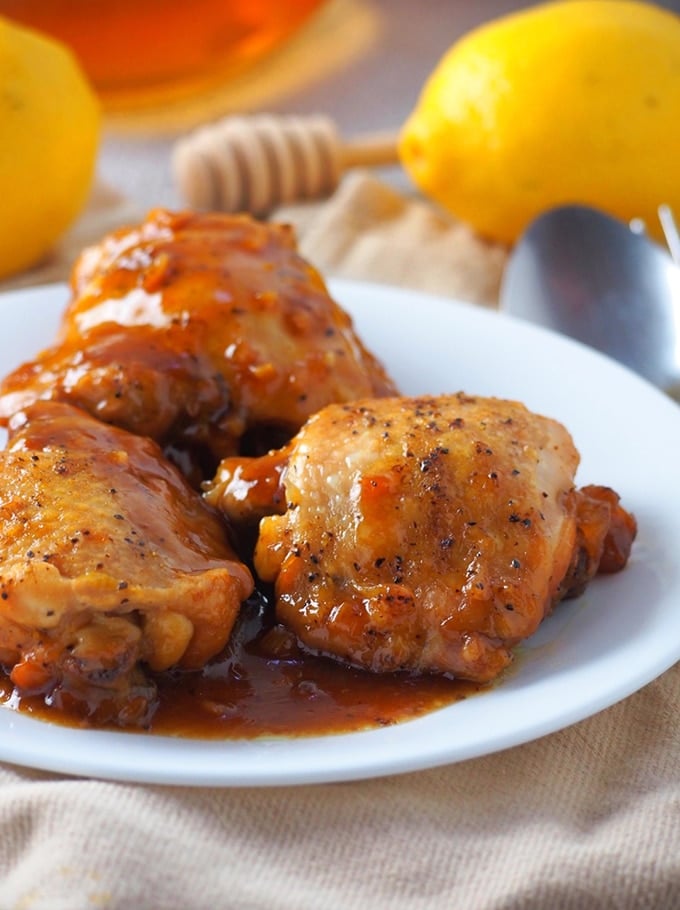 Instant Pot honey lemon chicken on a white plate with whole lemon on the side