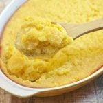 serving sweet corn pudding with a wooden spoon