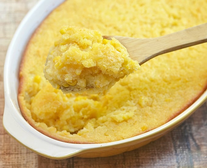 serving sweet corn pudding with a wooden spoon