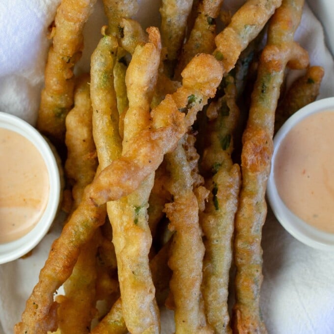 Beer-Battered Asparagus in a white dish with dipping sauces