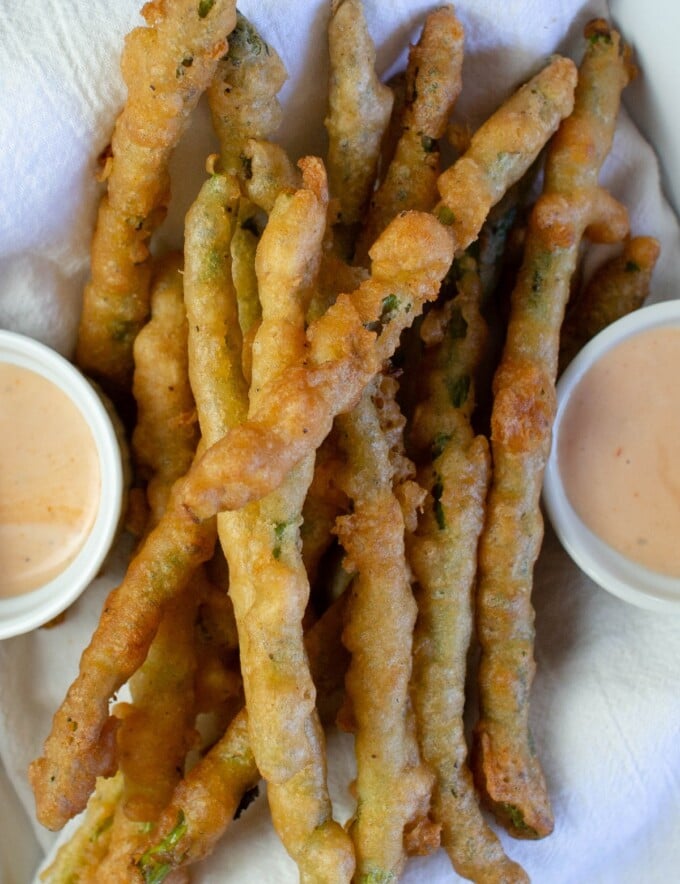 Beer-Battered Asparagus in a white dish with dipping sauces