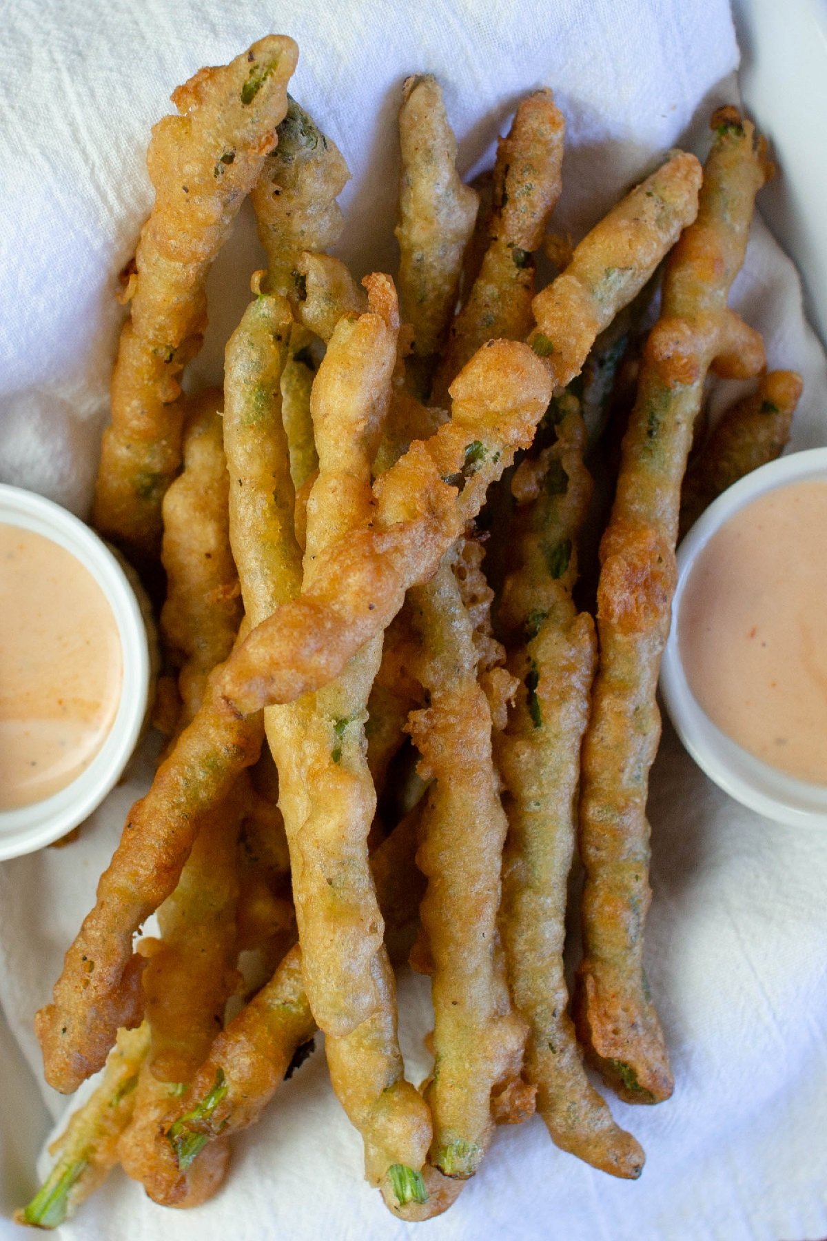 Beer-Battered Asparagus in a white dish with dipping sauces