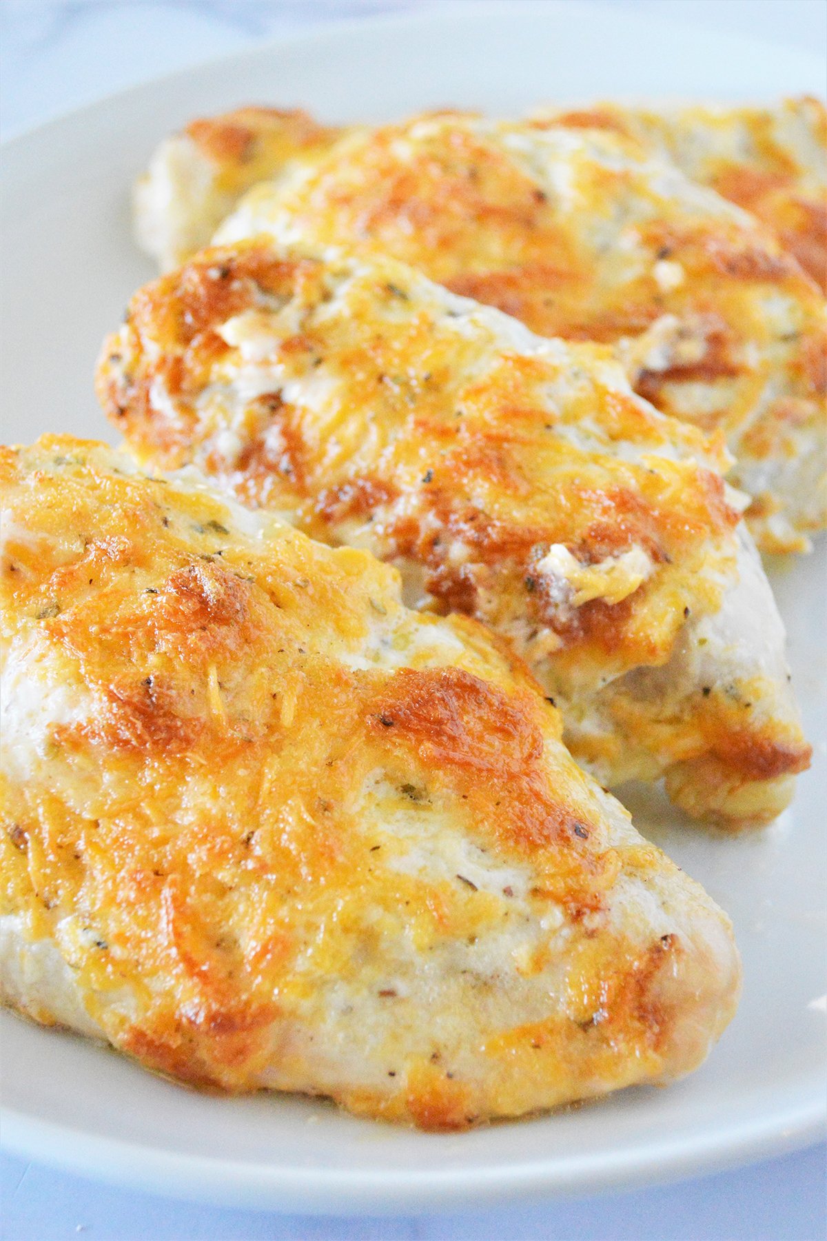 baked chicken breasts with mayo and cheese topping on a white plate