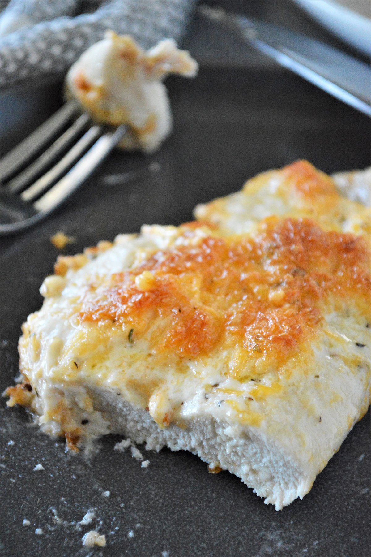 sliced baked chicken breast with cheese and mayo topping on a plate