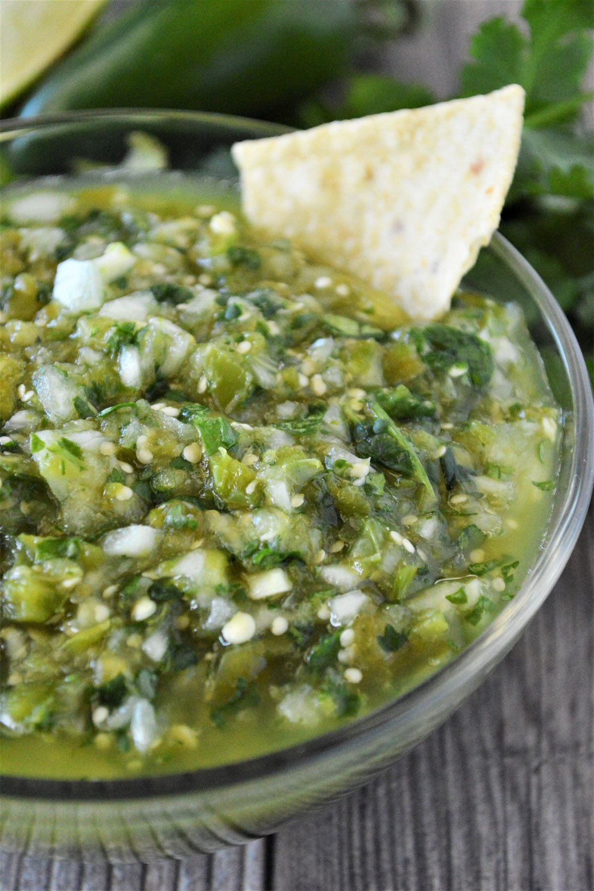 dipping corn chips in a bowl of salsa verde
