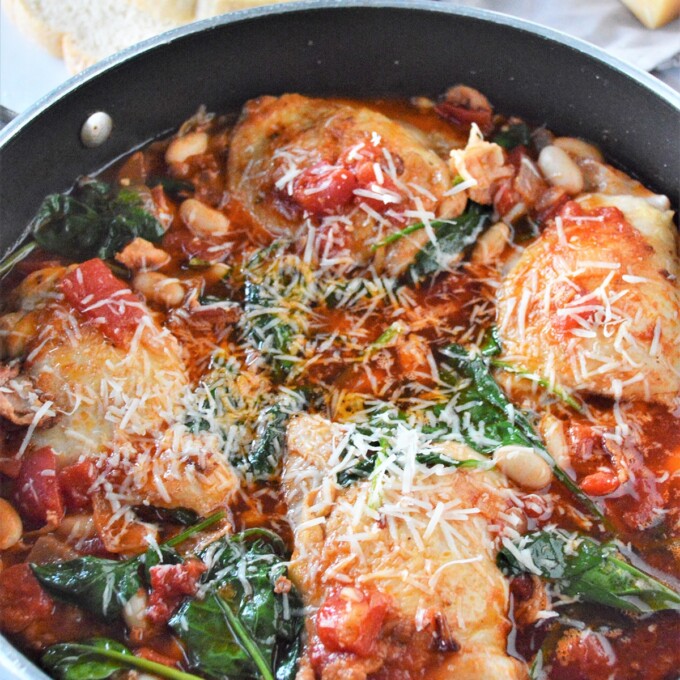 Tuscan chicken with white beans and spinach in a pan.