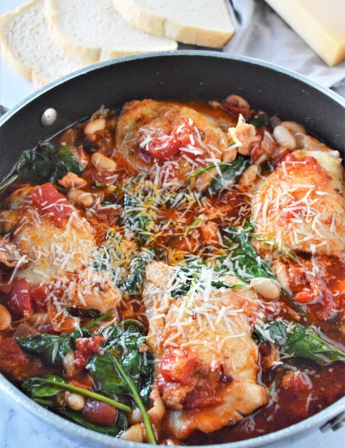 Tuscan chicken with white beans and spinach in a pan.