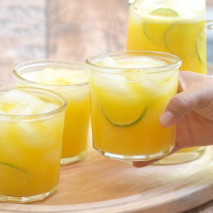 holding a glass of mango lemonade