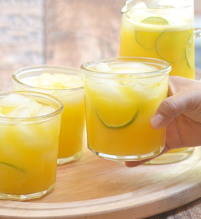 holding a glass of mango lemonade