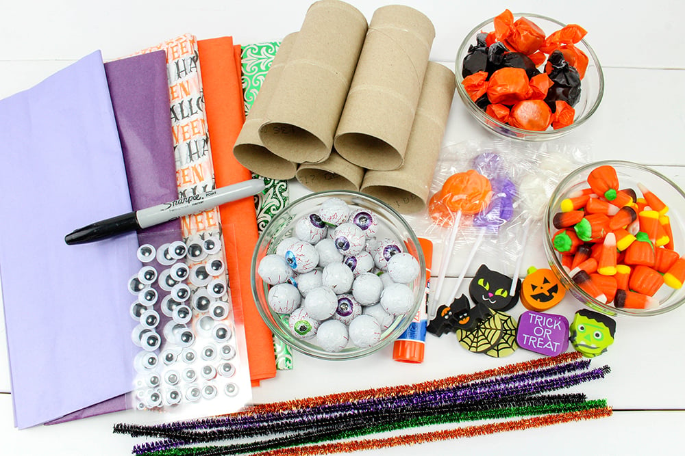 You only need simple supplies to make these Halloween party poppers, like tissue paper, candy, pipe cleaners, and paper towel cores!