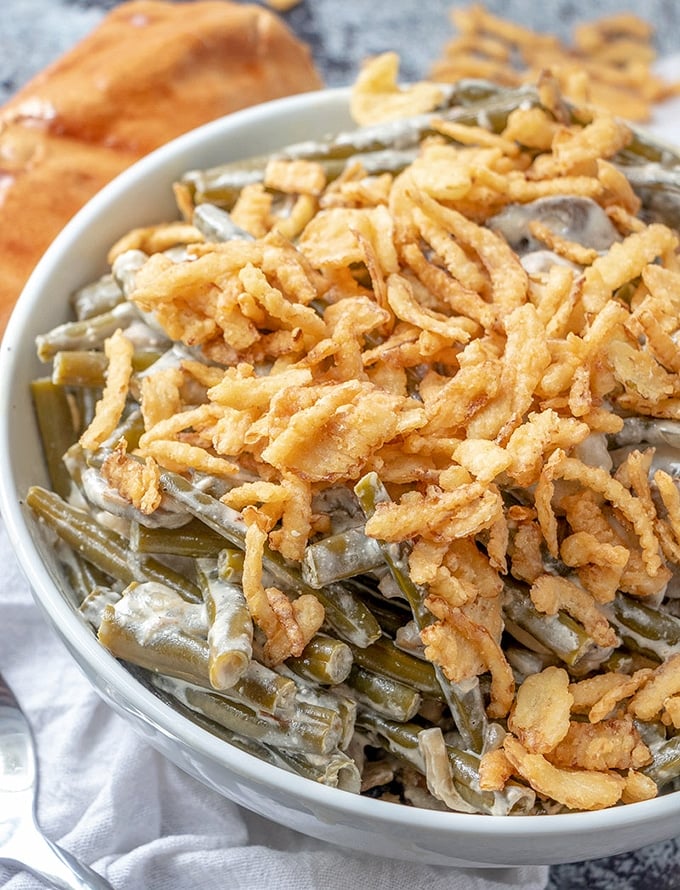 Slow Cooker Green Bean Casserole topped with french fried onions in a white serving bowl