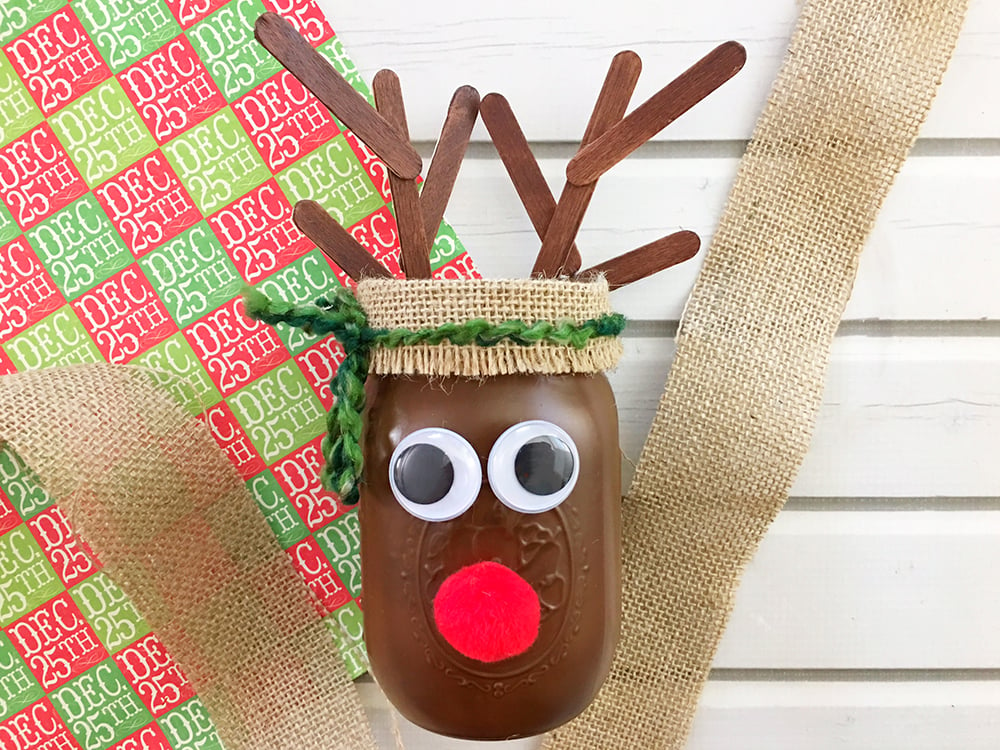 DIY Christmas Reindeer Mason Jar is perfect for holiday gift giving and home decorating. It's a fun and easy Christmas craft activity for the whole family!-tie green yarn around burlap into a bow