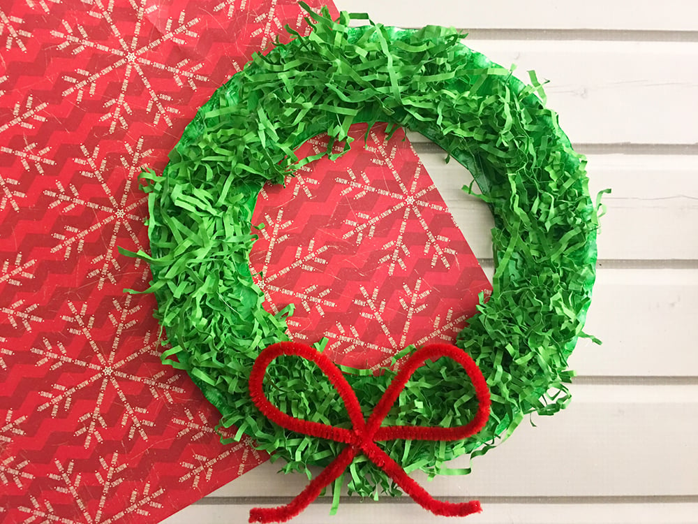 Homemade Christmas Wreath made with paper plate and shredded crinkle paper is a fun craft activity for the whole family and adds a festive touch to the holidays.