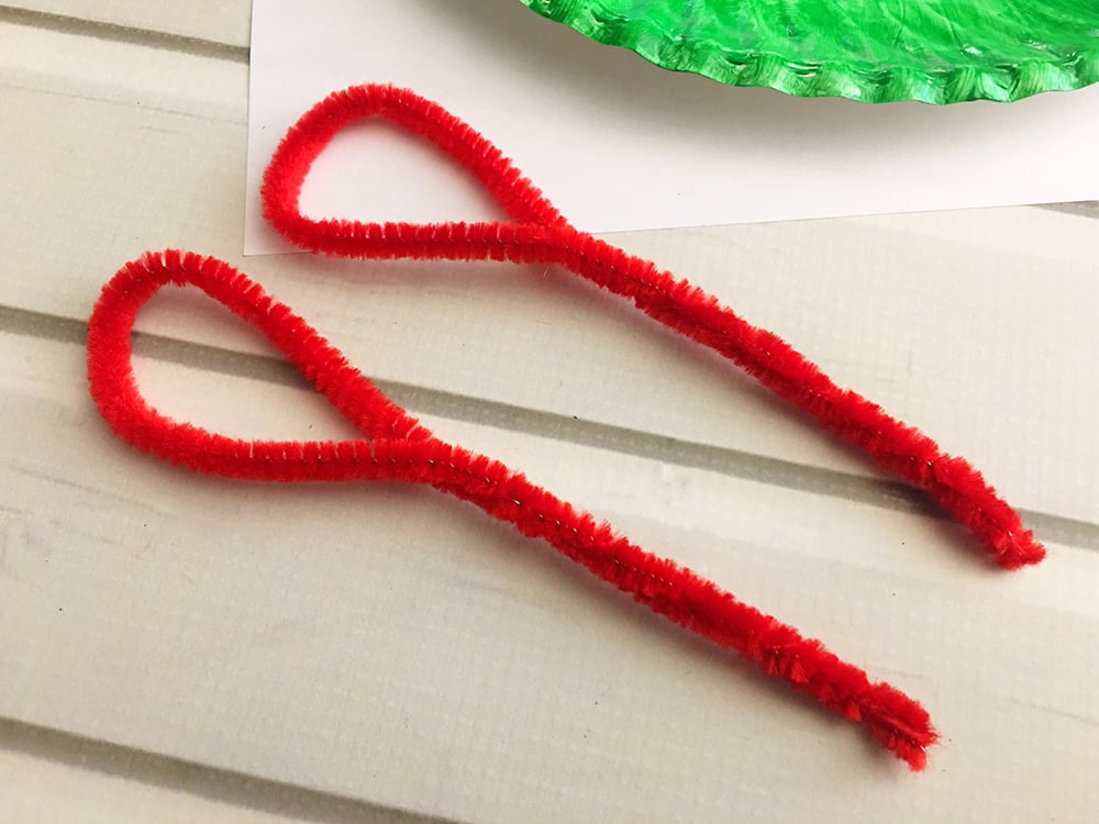 DIY Christmas Paper Wreath is a fun paper craft to do with the whole family. It's inexpensive to make and adds a festive touch to your holiday decor-fold two red pipe cleaners in half and twist into loops