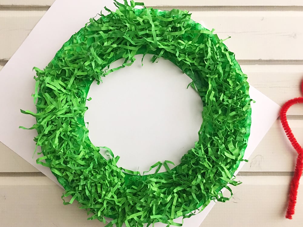 DIY Paper Christmas Wreath made with paper plate and shredded crinkle paper adds a festive touch to your holiday decor-trim off excess crinkle paper haging on the inside and outside of paper wreath