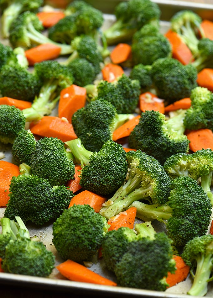 broccoli florets, sliced carrots and minced garlic on a baking sheet ready to roast