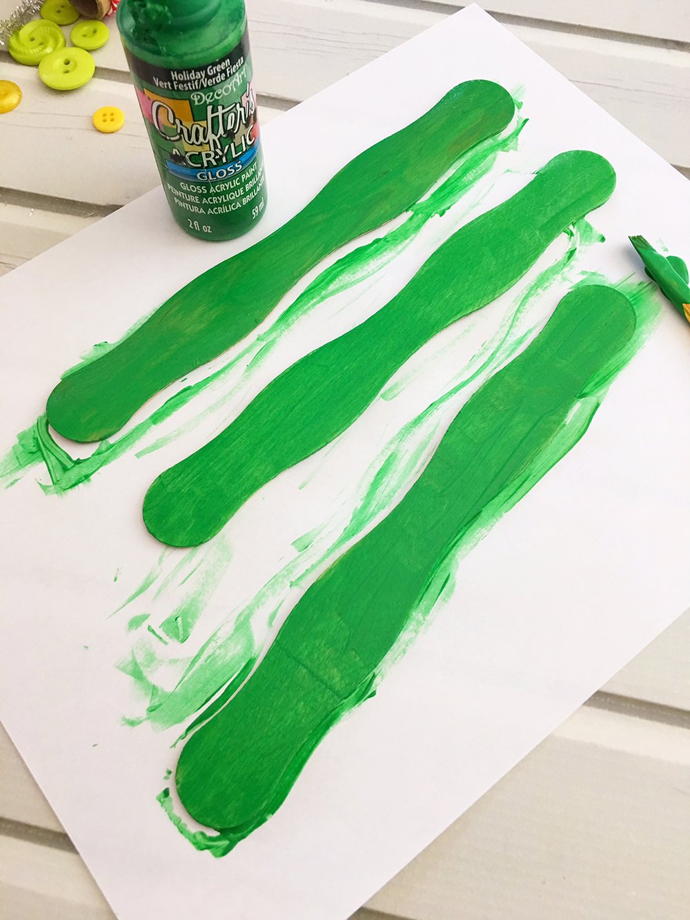 Paint the craft sticks green to make the base of your DIY Christmas tree ornaments. 
