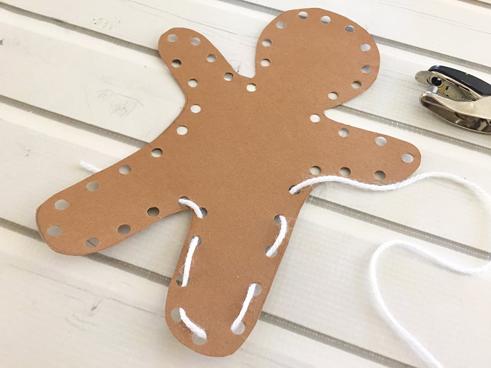 DIY Gingerbread Man Ornaments - Weave a piece of white yarn in and out of the holes and tie the two end pieces together in the back.