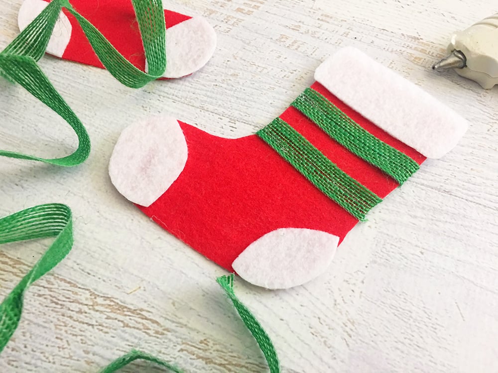 Felt Stocking Christmas Ornaments are an adorable addition to any holiday decor. So easy and fun to make with simple crafts supplies-glue green ribbons across the felt stocking