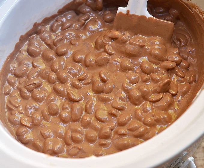making chocolate peanut clusters in a white crockpot