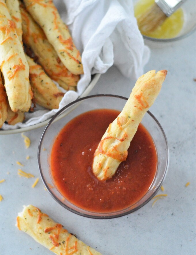 dipping Two-Ingredient Breadsticks in a bowl of marinara sauce.