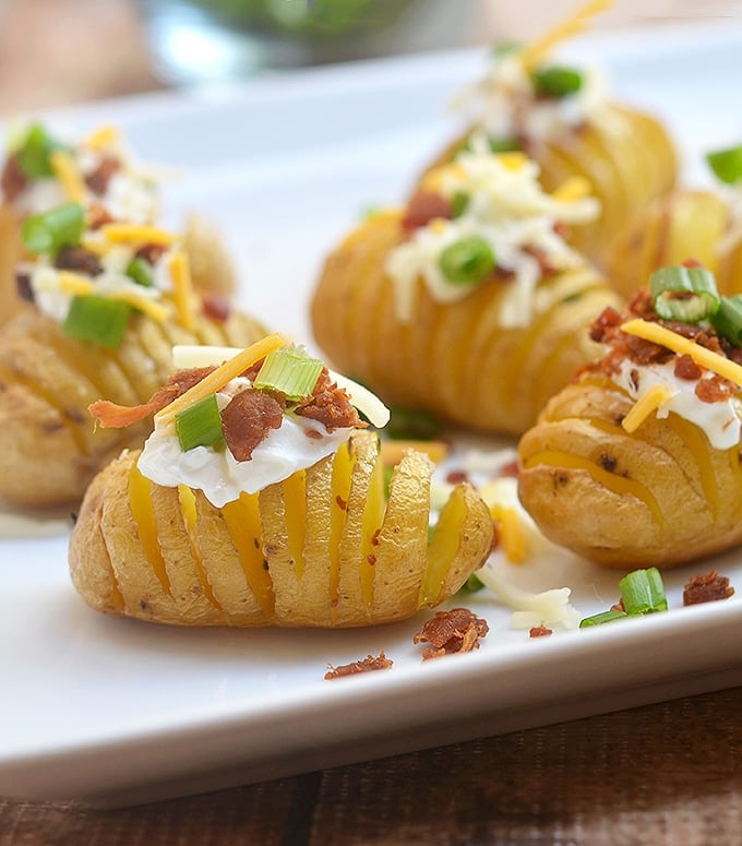 Mini Hasselback Potato Bites loaded with sour cream, crisp bacon, shredded cheese and green onions.