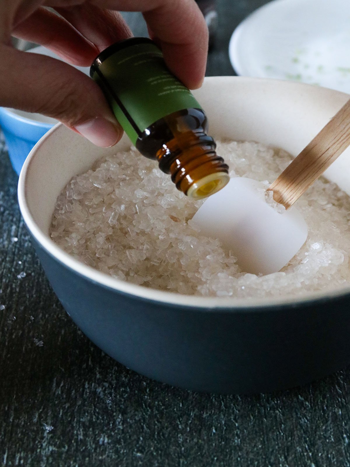 adding essential oil to a bowl of salts