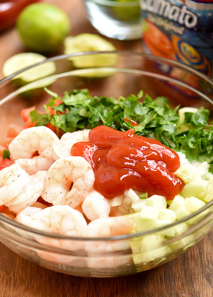 cooked shrimp and chopped cucumber, tomatoes, onions, cilantro, chili peppers, and ketchup in a large bowl to make coctel de camaron