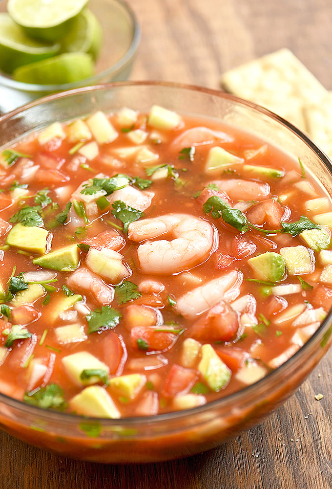 Coctel de Camaron with cucumber, tomato, onion, cilantro, chili peppers, clamato juice and avocados in a clear bowl