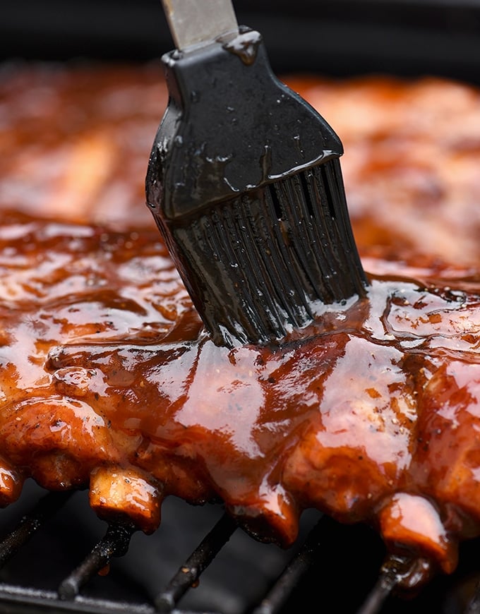 basting grilled baby back ribs with cola BBQ sauce