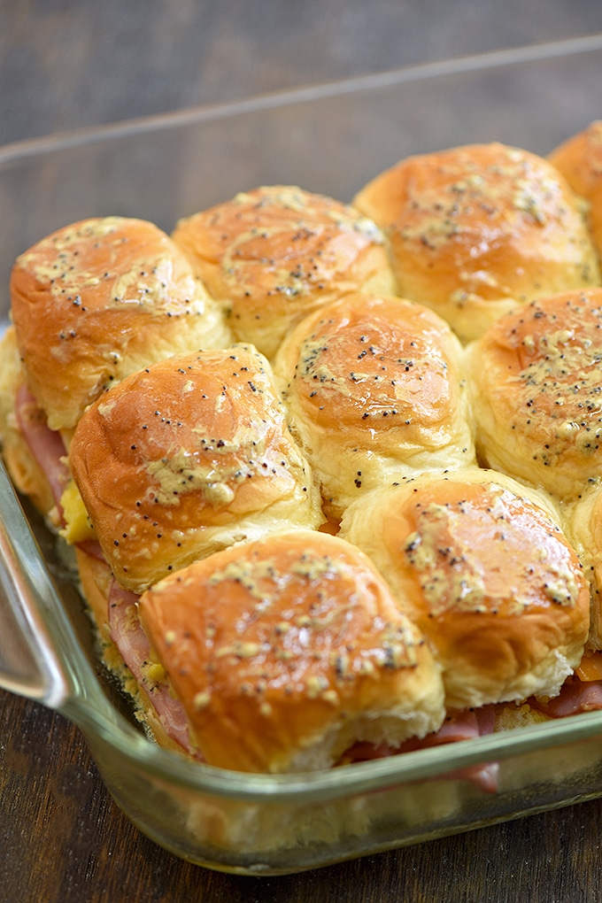 breakfast sliders with ham, eggs, cheese brushed with dijon mustard glaze in a casserole dish to bake