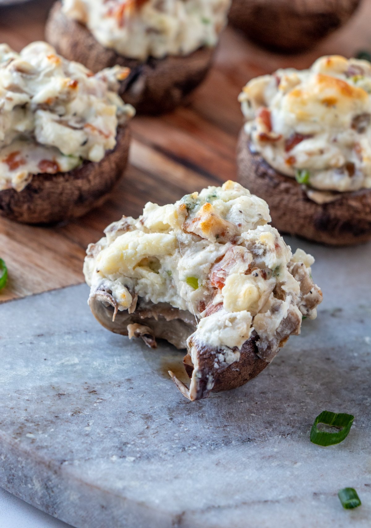 cut mushroom bites with cream cheese stuffing on a serving board