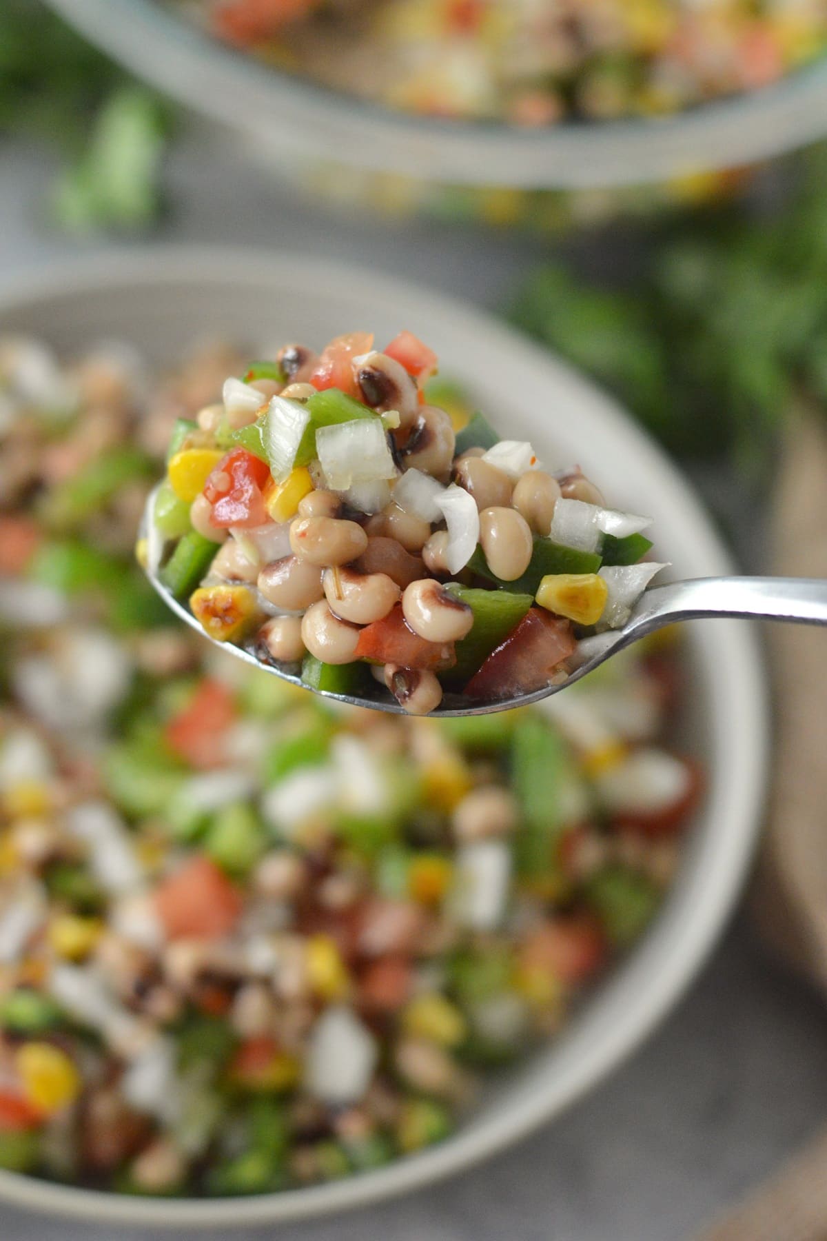 serving Texas caviar dip with a spoon from a white bowl.