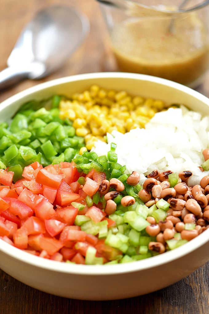 black-eyed peas, grilled corn kernels, and tomatoes, bell peppers, onions, and jalapenos in a large bowl for making texas caviar