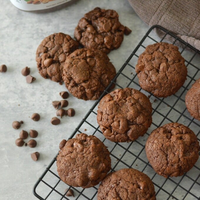 Nutella cookies on wire rack and chocolate chips in the background.
