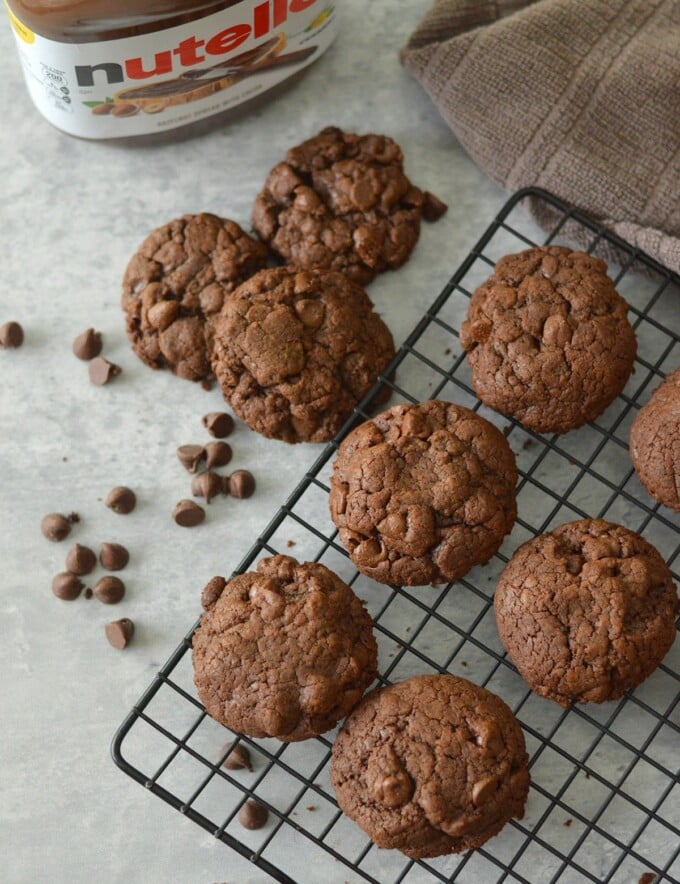 Nutella cookies on wire rack and chocolate chips in the background.