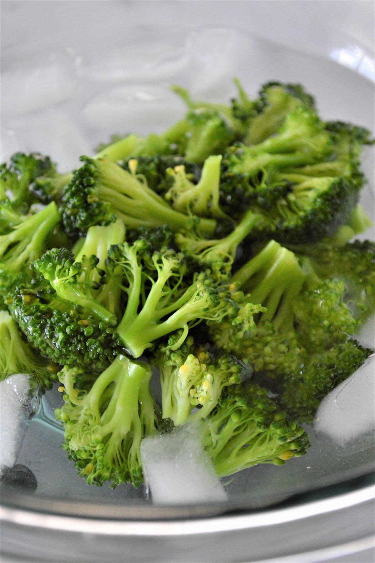 blanced broccoli florets in a bowl of iced water