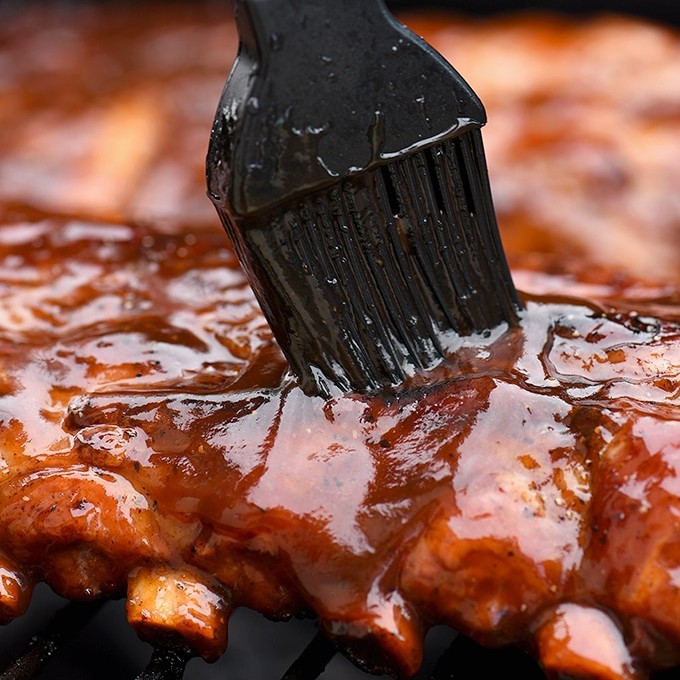 basting grilled baby back ribs with cola BBQ sauce