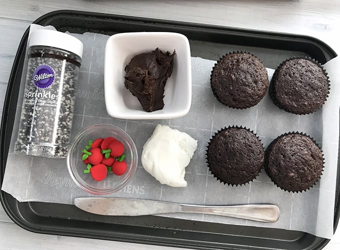 chocolate cupcakes, white fondant, chocolate frosting, candy decorations on a baking sheet to make back-to-school cupcakes