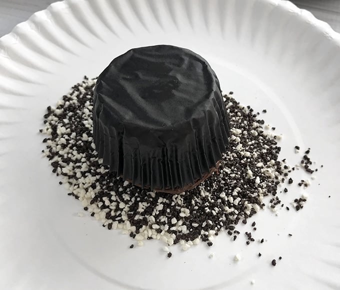 frosted chocolate cupcake being dipped in candy sprinkles