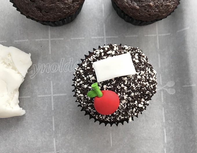 Back-to-school cupcakes decorated with candy sprinkles, white fondant and apple icing candies