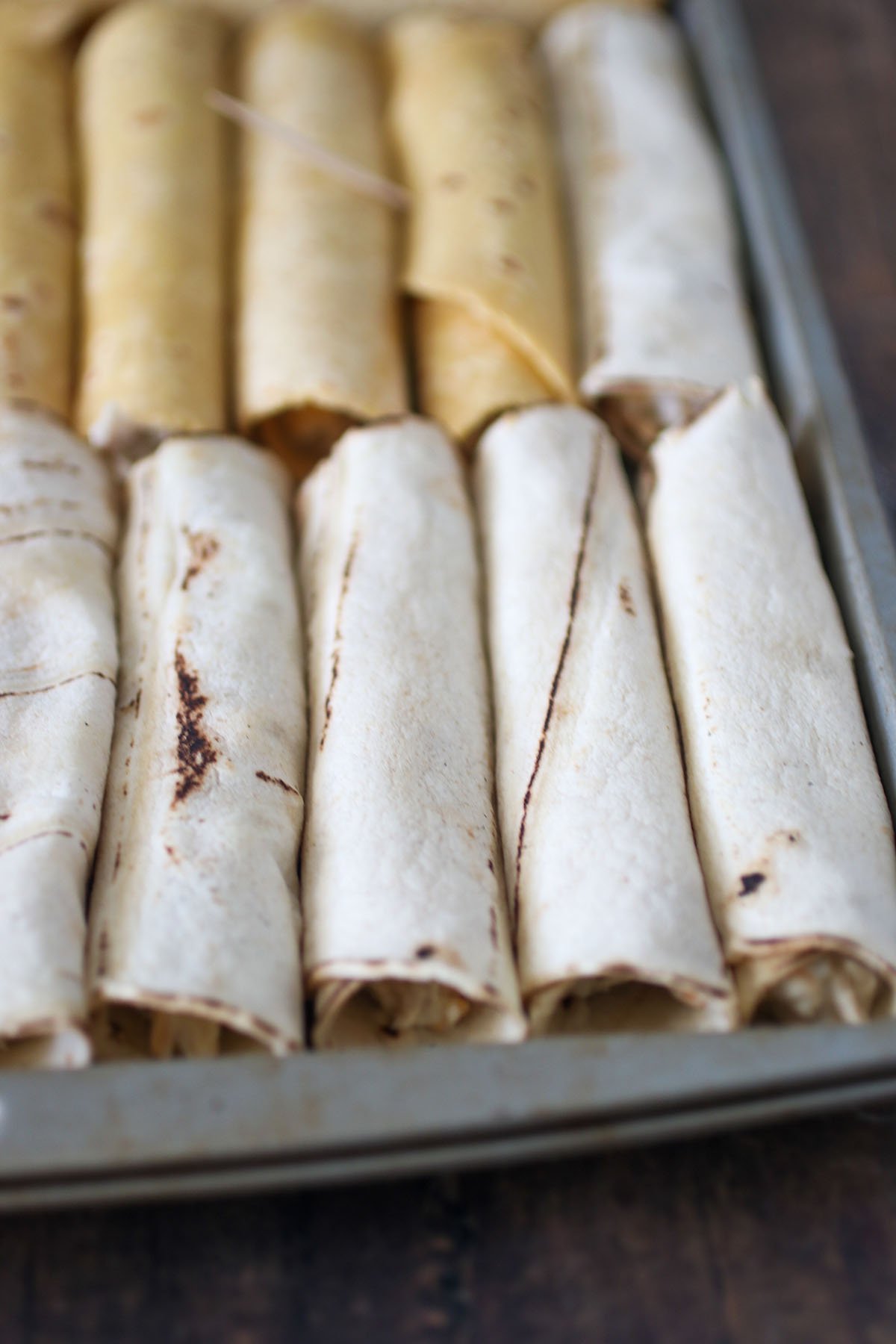 rolled up chicken taquitos on a baking sheet