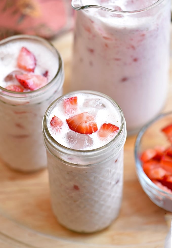 strawberry aqua fresca with milk in clear serving glasses and pitcher