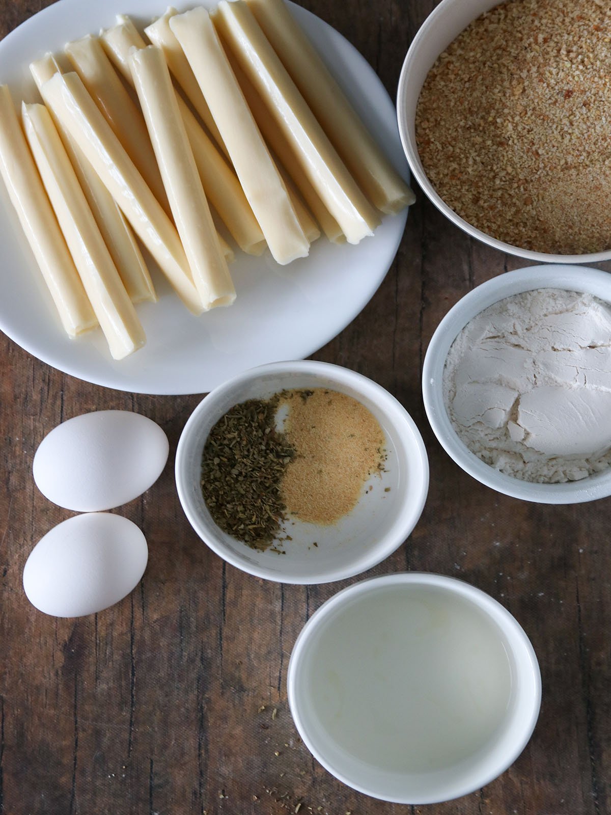 cheese sticks, bread crumbs, eggs, flour, garlic powder, Italian seasoning, oil