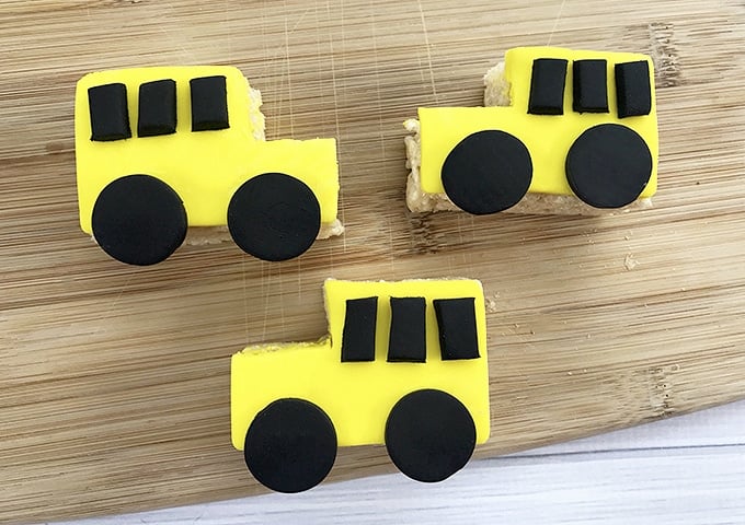 yellow Rice Krispies treats shaped like a school bus with black fondant wheels and windows