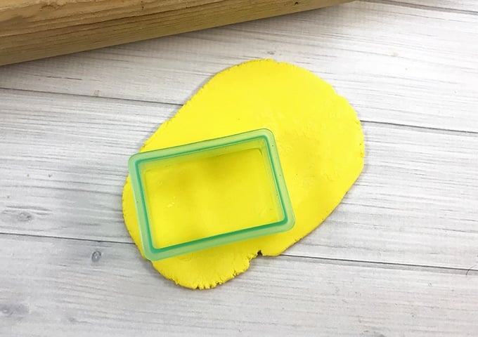 cutting yellow fondant with rectangular cookie cutter to make School Bus Rice Krispie Treats